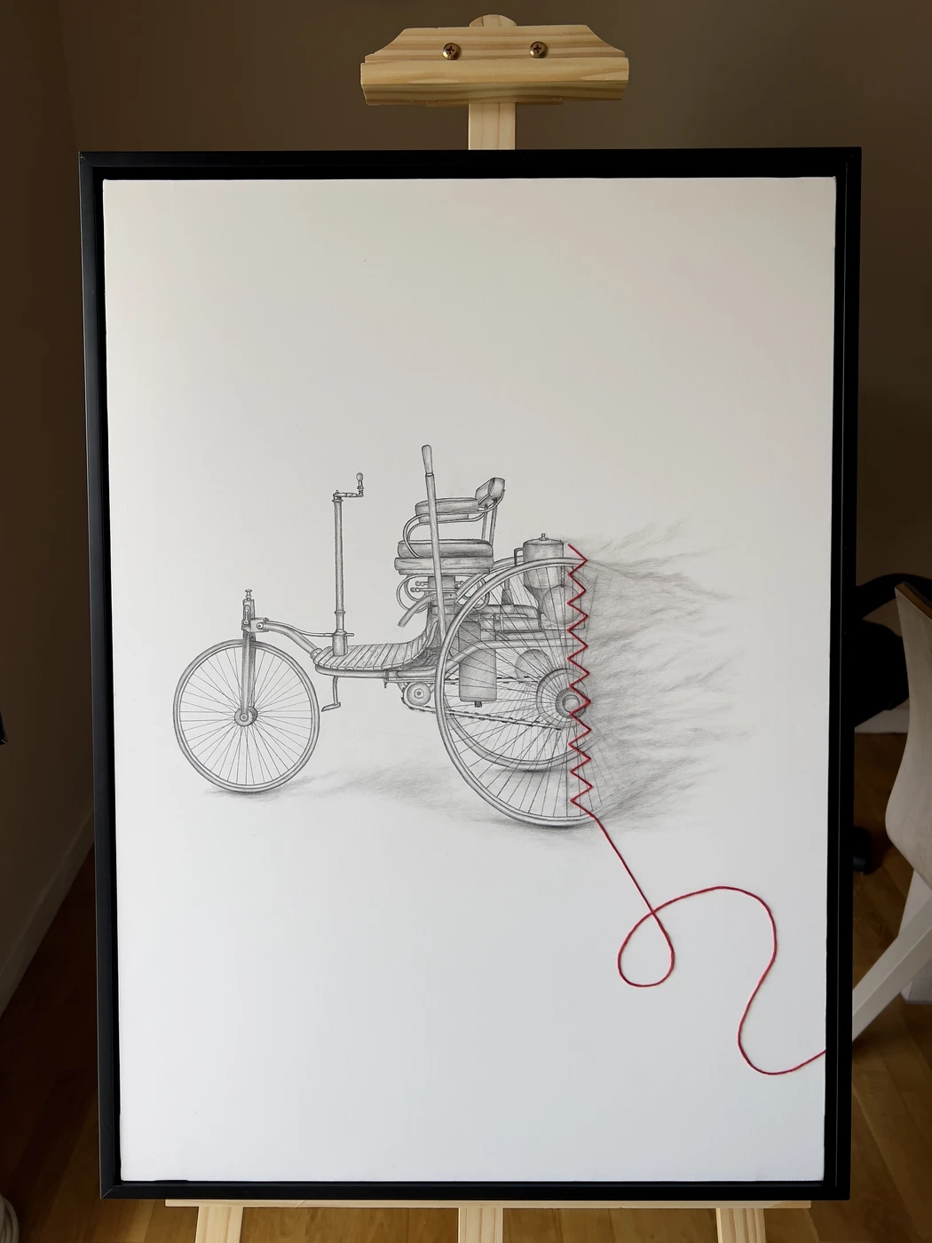 Detalle de la primera pieza del díptico: el Benz Patent-Motorwagen dibujado en grafito con la costura de hilo rojo sobre caballete