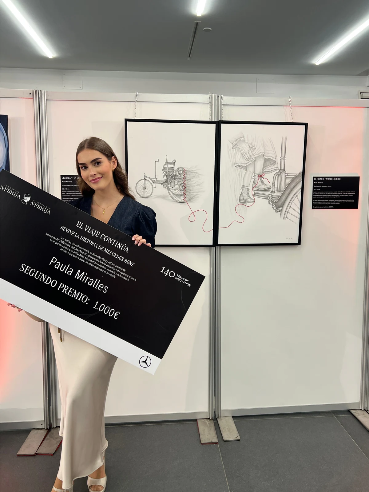 Paula Miralles recogiendo el segundo premio del concurso de los 140 años de Mercedes-Benz junto a su díptico